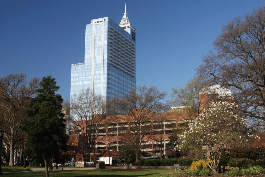 green space with blooming tree in front of tall business building in Downtown Raleigh